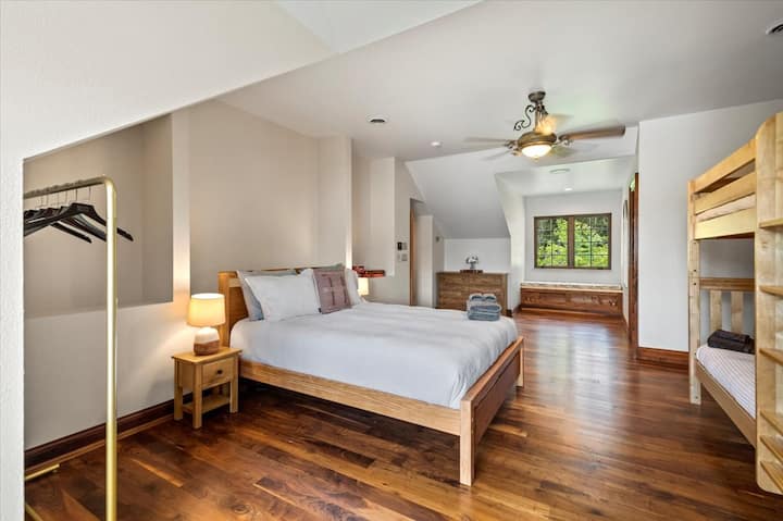 The upstairs features a kid’s den with a full-length window overlooking the lake with two bedrooms on either side. Each bedroom features a queen bed, a twin-over-twin bunk bed, a workspace area, and a half bath.