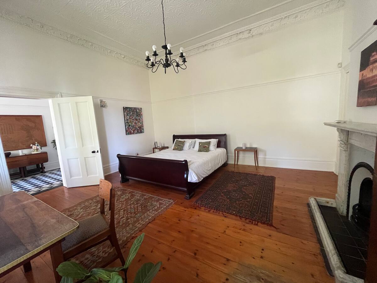 King bed on wooden floors beside the fireplace in the garden king room at Utopia Cape Town