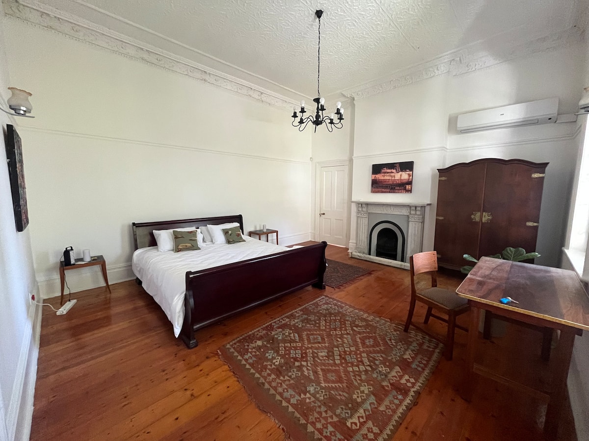 King bedroom with fireplace and high ceilings at Utopia co-living in Fresnaye, Cape Town