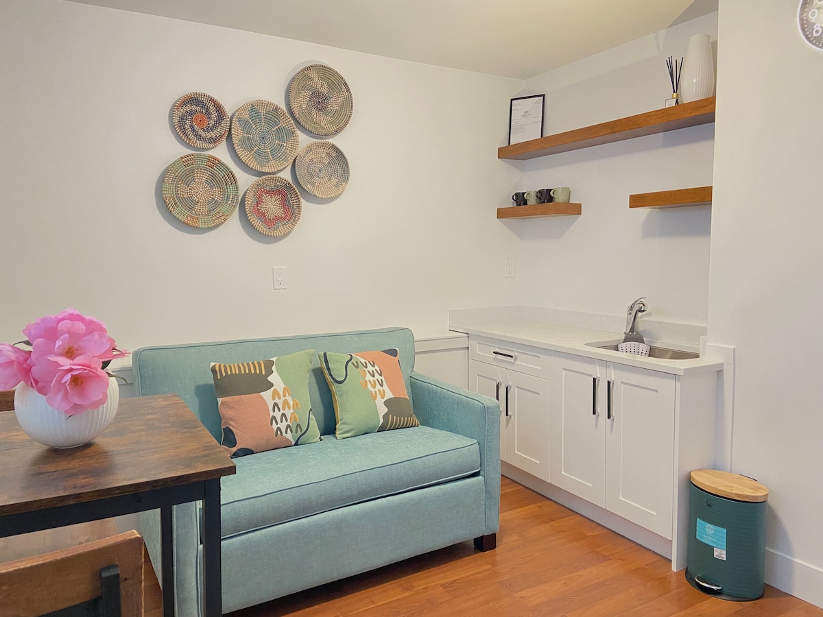 ห้องนั่งเล่นพร้อมอ่างล้างหน้าและเคาน์เตอร์เพื่อช่วยเตรียมอาหารที่เรียบง่ายและรวดเร็ว โซฟาสามารถดึงออกมาเป็นเตียงแฝดหันหน้าไปทางสมาร์ททีวีขนาด 49 นิ้ว