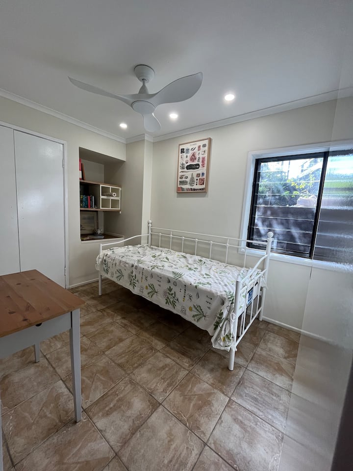 מיטת יחיד נוחה ושולחן קטן.