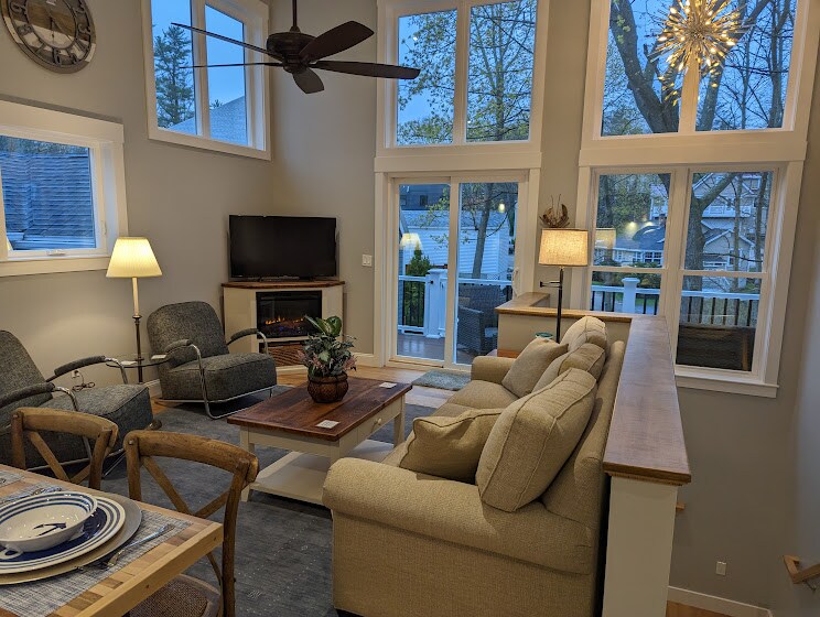 The open-concept living area is equipped with comfortable seating options, including cozy armchairs and a spacious sofa. Natural light floods in through large windows, creating a bright atmosphere. A modern coffee table is placed centrally, and a flat-screen television is mounted on the wall.