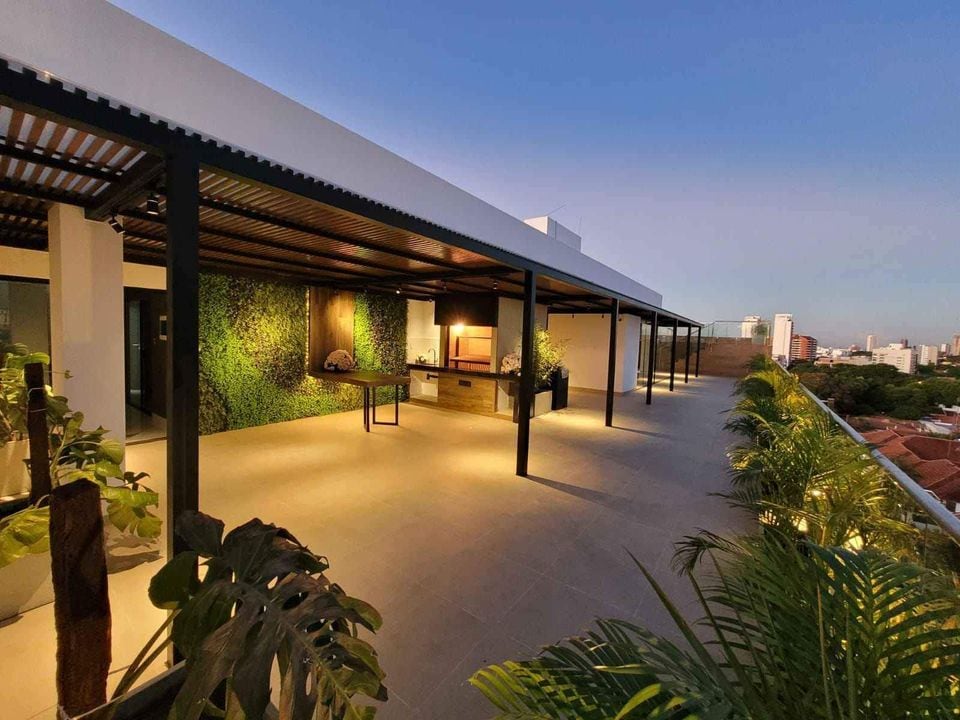 A spacious rooftop terrace is featured, complemented by areas of greenery and equipped with a barbecue grill. Ample seating is provided under a shaded pergola, offering city views. The modern design promotes relaxation and easy social gatherings.