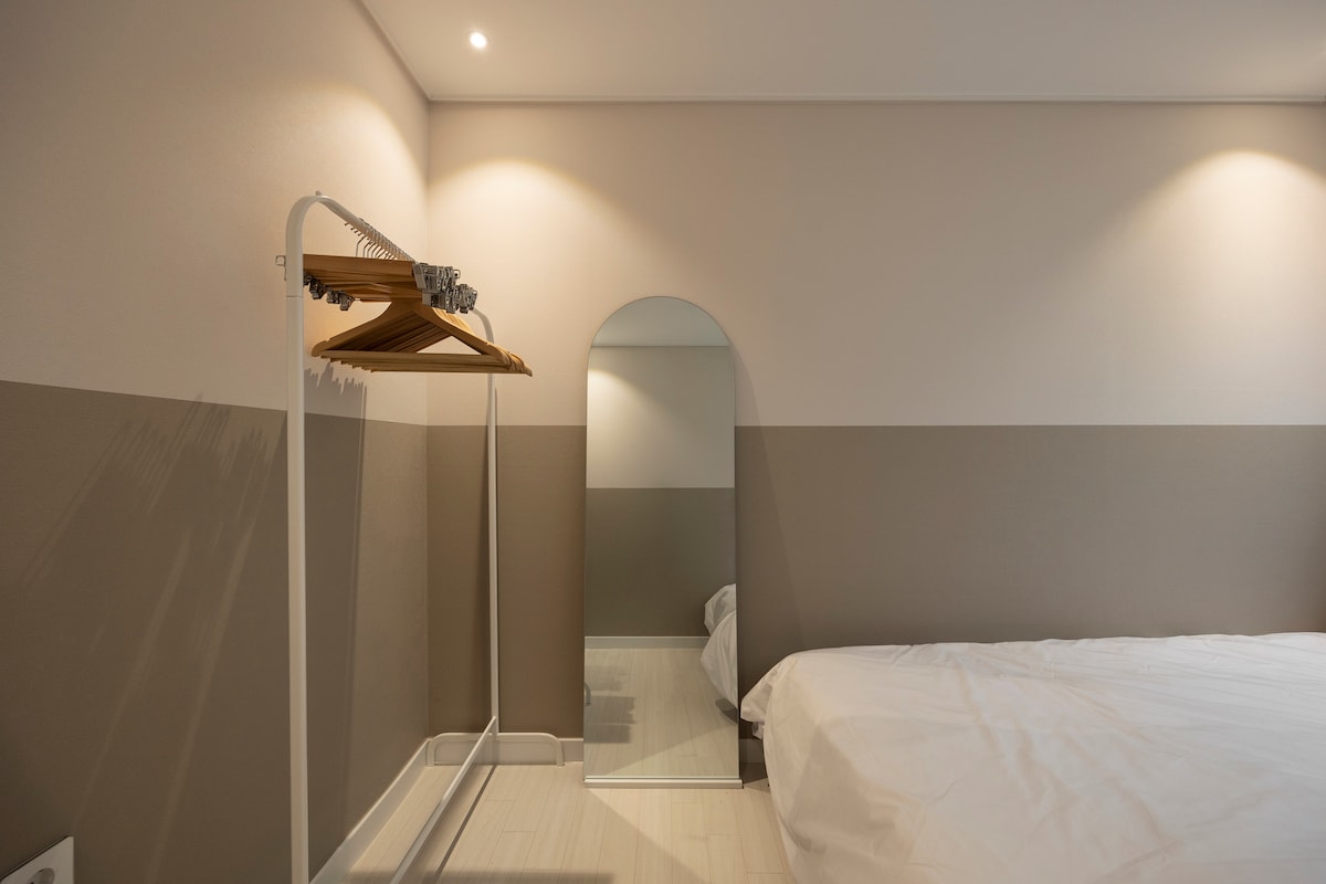 Спалнята има огледало в цял ръст и закачалки за окачване на закачалки и закачалки.