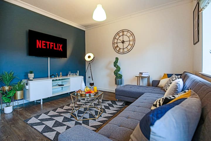 ห้องนั่งเล่นที่อบอุ่นพร้อมโซฟาเข้ามุมที่สะดวกสบายและสมาร์ททีวีขนาด 50 นิ้วพร้อมการสมัครสมาชิก Netflix