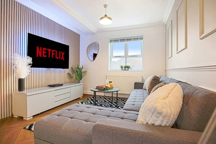 Una acogedora sala de estar con un cómodo sofá de esquina y un televisor inteligente de 55 pulgadas con Sky TV y suscripción a Netflix incluidos.