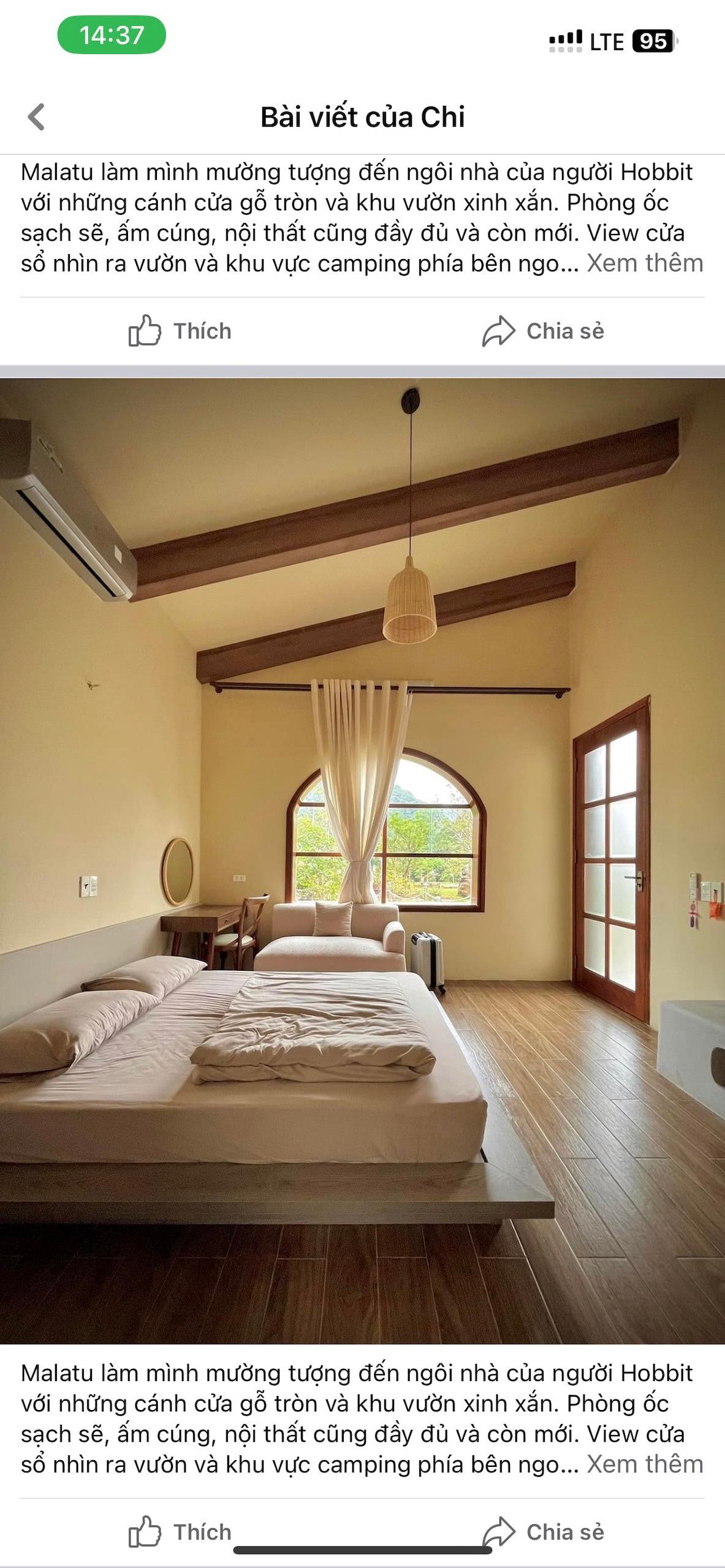 A cozy sleeping area features a spacious bed with clean linens. The room is illuminated by natural light through a large arched window, with wooden beams adding character to the ceiling. A rustic wooden floor complements the warm atmosphere.