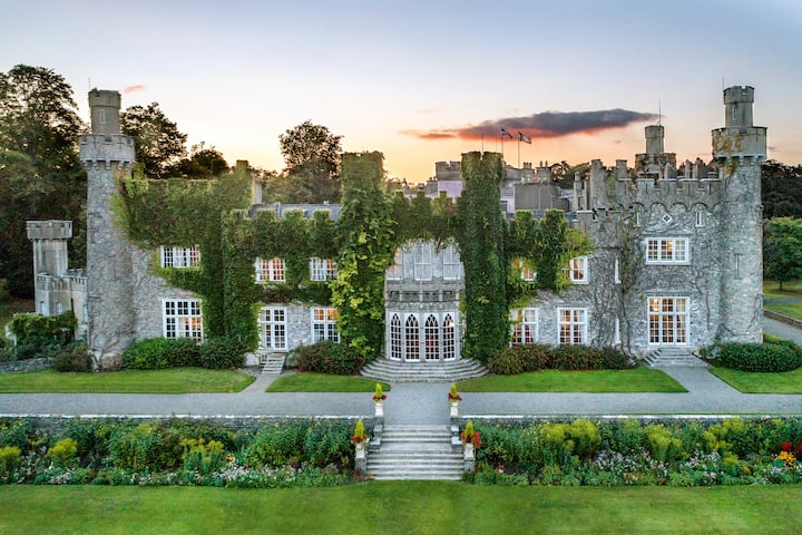 Esterno di Luttrellstown Castle con muri in pietra coperti di edera e giardini formali