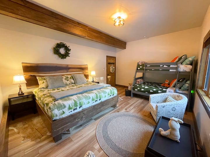 Chumba cha kulala cha ghorofa ya kwanza kimepambwa vizuri ili kuleta mandhari ya nje. King size bed + twin over full size bunk beds with children corner and sitting area with 2 club chair, storage ottoman/coffee table. Dari kubwa, chumba chenye hewa safi chenye mwonekano wa ua wa mbele. 