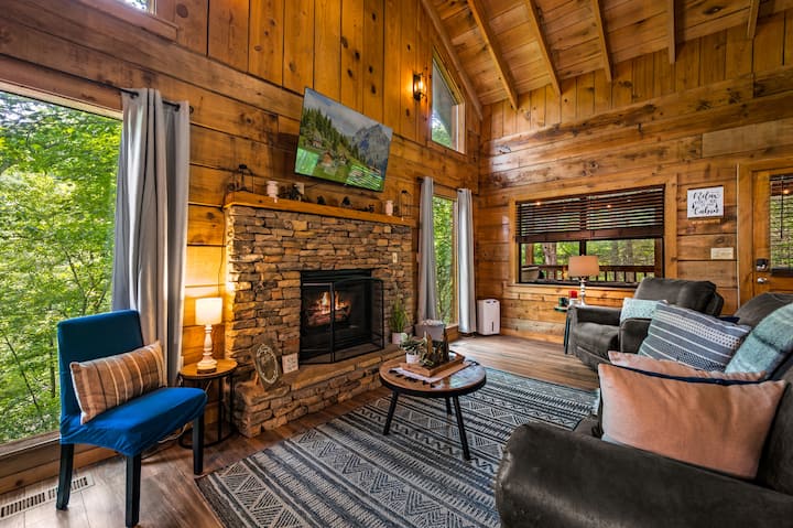 Relájate en nuestra acogedora sala de estar con una chimenea de piedra y vistas panorámicas al bosque, el lugar perfecto para pasar las noches frías o pasar tiempo de calidad con la familia