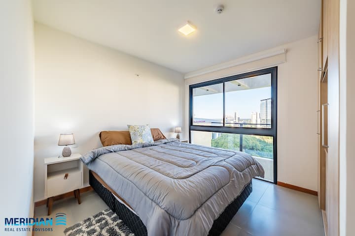 Ფართო ორადგილიანი ოთახი მსუბუქი მაგიდებით, იალქნიანი ნავები და საწოლის საგებები.