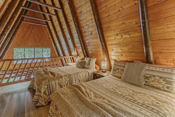 Удобна спална соба на поткровје со брачни кревети и топол дрвен ентериер