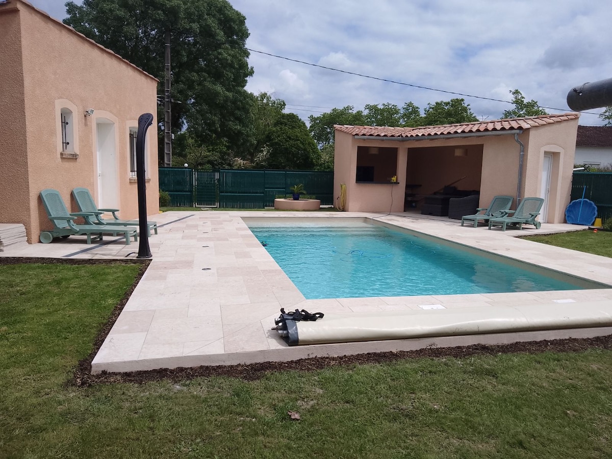 A private swimming pool is surrounded by well-maintained grass, with several lounge chairs placed nearby. A shaded outdoor living area features comfortable seating and is complemented by a flat-screen TV. The surrounding space is spacious and designed for relaxation.