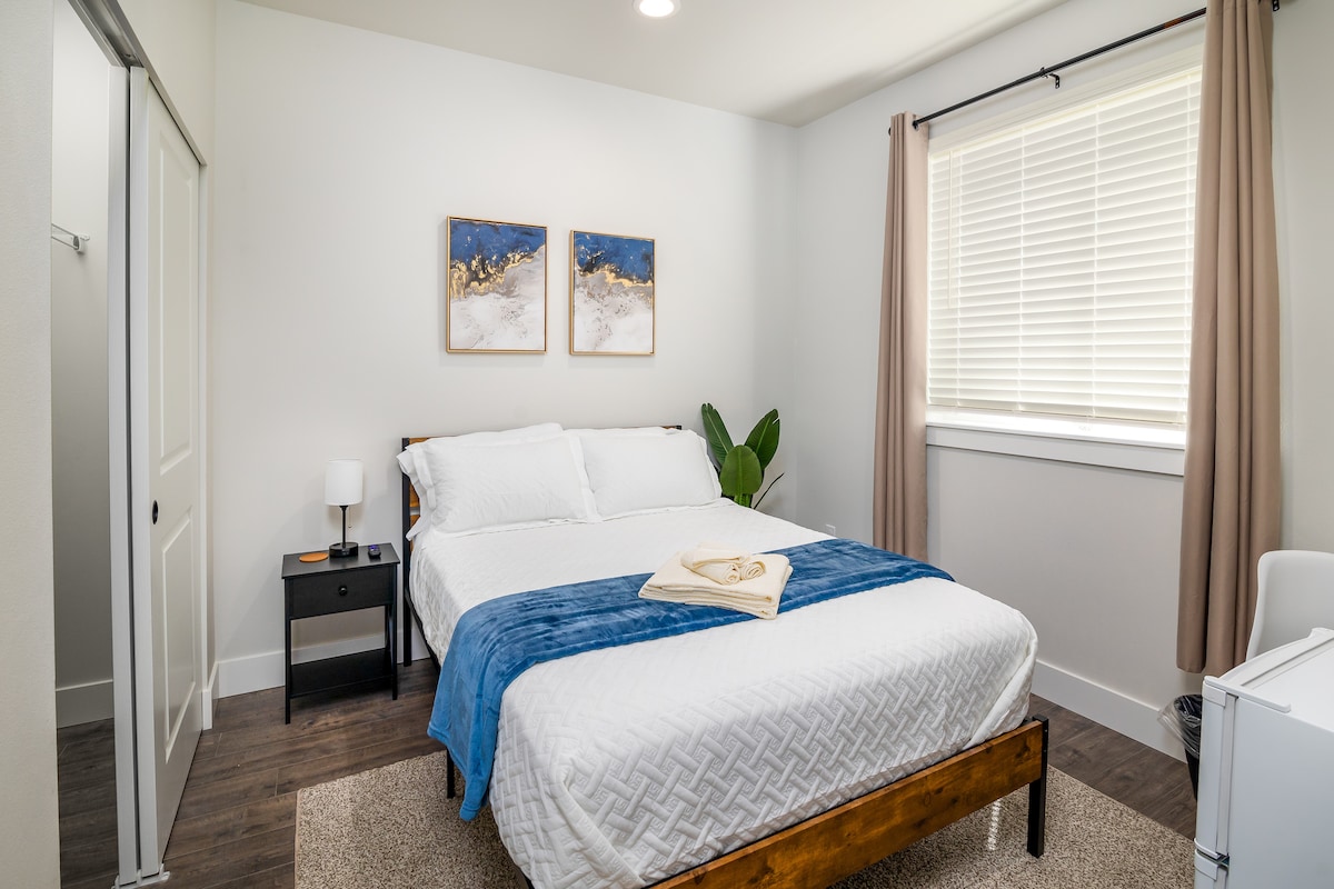 Cama de tamaño completo, con espacio de trabajo, mini refrigerador y televisión inteligente.