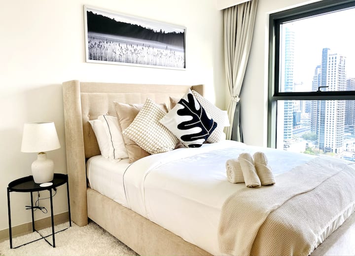 El dormitorio 2 cuenta con una cama tamaño queen con ropa de cama acogedora en un espacio moderno y cuidadosamente diseñado. Grandes ventanales enmarcan impresionantes vistas del hermoso centro de Dubái, creando un refugio relajante en el corazón de la ciudad.