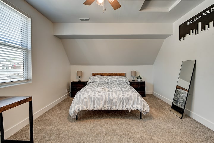 ห้องนอนสำรองชั้นบนพร้อมเตียงควีนไซส์และพื้นที่ทำงานที่บ้าน