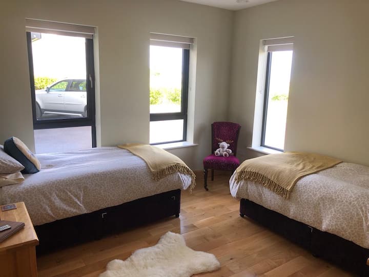 Vitanda viwili vikubwa vya starehe ambavyo vinaweza kuwa zip na kuunganishwa ili kutengeneza Super King. Chumba hiki cha kulala cha ensuite kinatoa maoni juu ya ziwa jipya huko Dunfanaghy na zaidi unaweza kuona pwani ya Tramore.