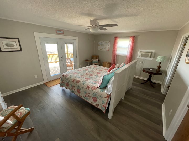 Ubicado en el nivel principal, el dormitorio Coral es tu dormitorio principal con una cama tamaño king. Disfruta de una vista relajante del agua desde la comodidad de tu cama o disfruta de un café en la espaciosa terraza cubierta.