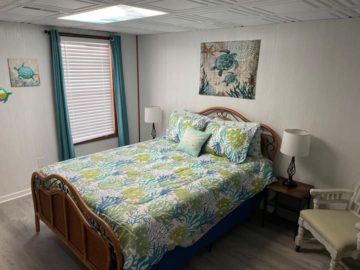 Sala de tortugas marinas. Este dormitorio queen de nivel inferior tiene una hermosa vista al agua y acceso compartido al baño/ducha completo del nivel inferior y al armario Jack-and-Jill. 