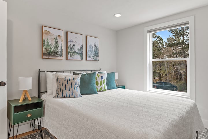 Kitanda cha starehe chenye ukubwa wa malkia kinachoambatana na meza ndogo 2 za pembeni na taa za kusoma zenye mwonekano mzuri wa nje