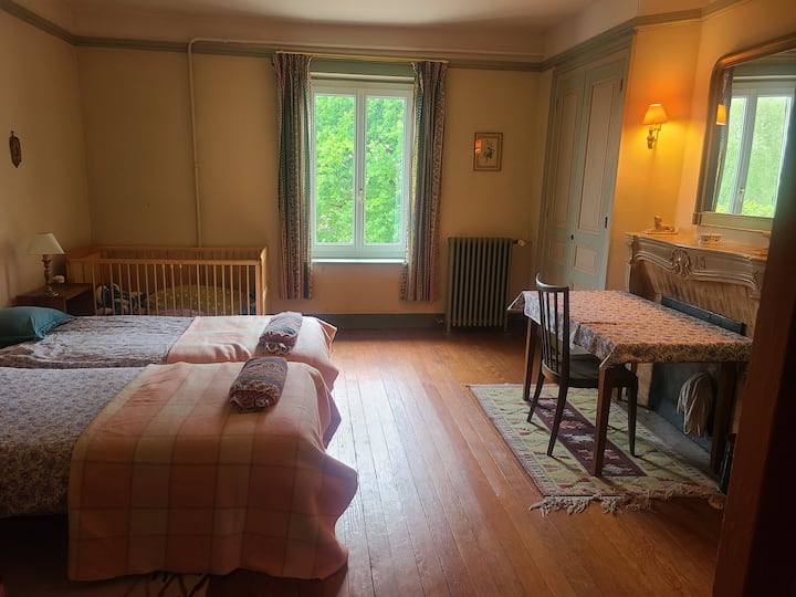 la chambre verte comprenant 2 lits simple,  un lit à barreaux, une table de travail et un cabinet de toilette