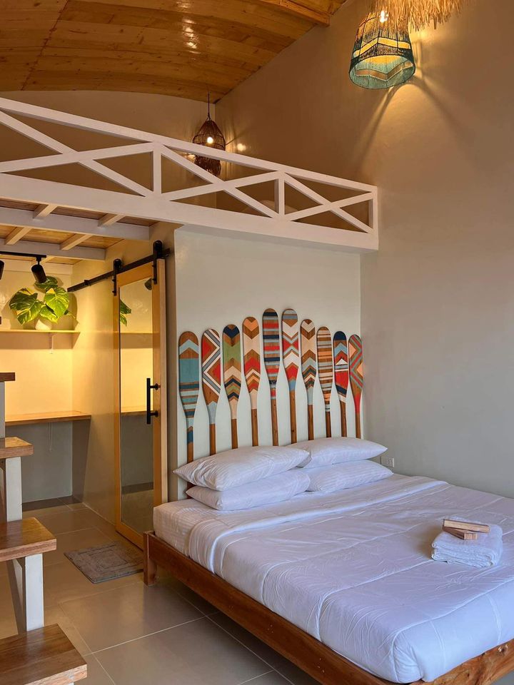 A cozy bedroom features a spacious bed with crisp linens. Colorful ski-themed artwork decorates the wall behind the bed. Wooden accents are present in the furnishings, and a warm light fixture adds a soft glow to the room.