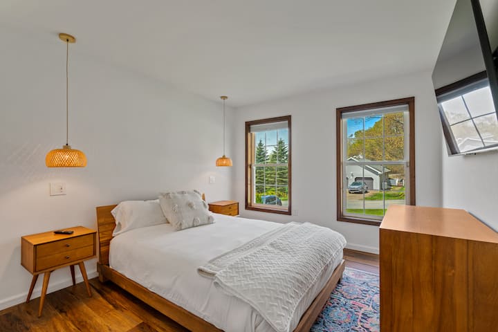 غرفة بسرير كوين وتلفزيون ذكي، مع إضاءة مريحة بجانب السرير