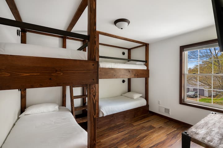 غرفة بسرير بطابقين وتلفزيون ذكي ومصابيح قراءة مثبتة على الحائط مع إمكانية شحن USB