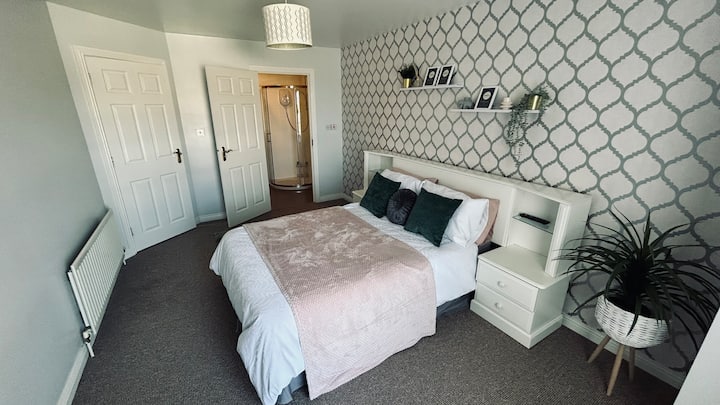 Dormitorio principal cama doble tamaño con cajones de cama y lámparas de lectura junto a la cama a ambos lados de la cama. Televisor inteligente montado en la pared acompañado por un cofre de 6 cajones para un montón de espacio de almacenamiento o un área para prepararse. El baño privado es una ventaja.