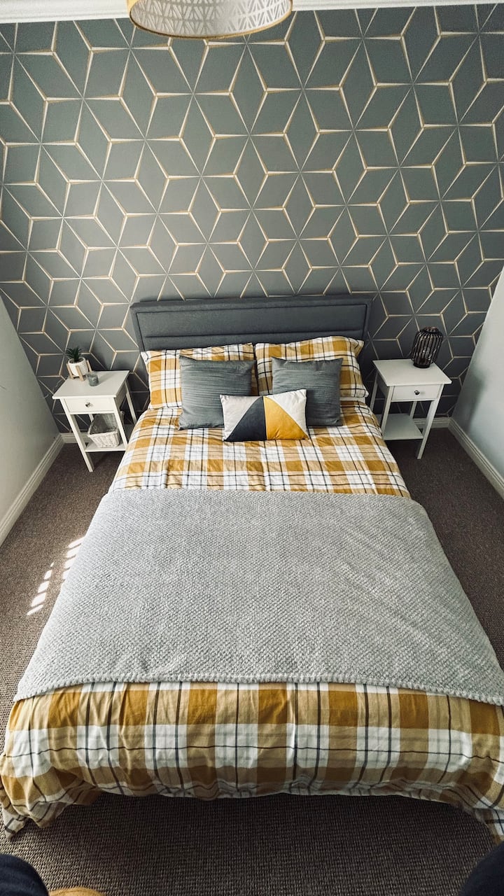 Dormitorio 2, que es la habitación de tamaño medio con cama doble, cajonera y televisión con vista libre. Enchufes a cada lado de la cama.