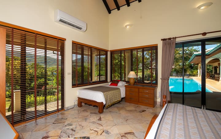 Chambre 4 - Après de vastes rénovations (février 2021).  Nous avons maintenant des stores en bois ouvrant la vue sur la piscine et le jardin. Garde-robe et espace de travail neufs.