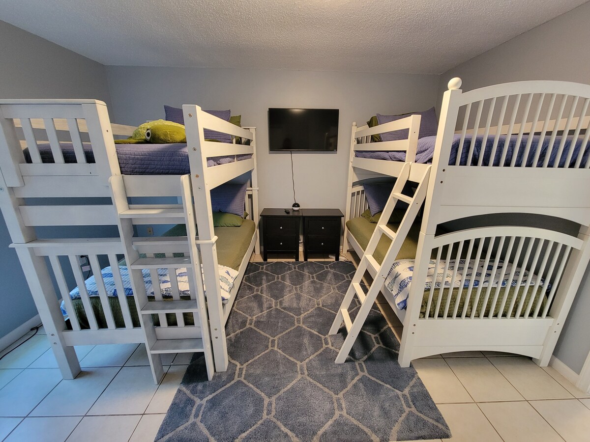 Dhomë e përbashkët me 4 krevate tek dhe televizor inteligjent. 