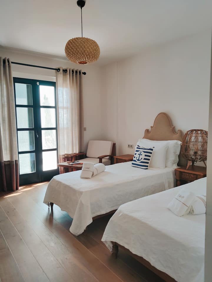 Kjo dhomë gjumi në katin përdhes ka gjithashtu dy krevate tek 90x200, dy tavolina pranë krevatit dhe një banjë private.
Nga kjo dhomë mund të shkosh direkt në kopsht dhe pishinë