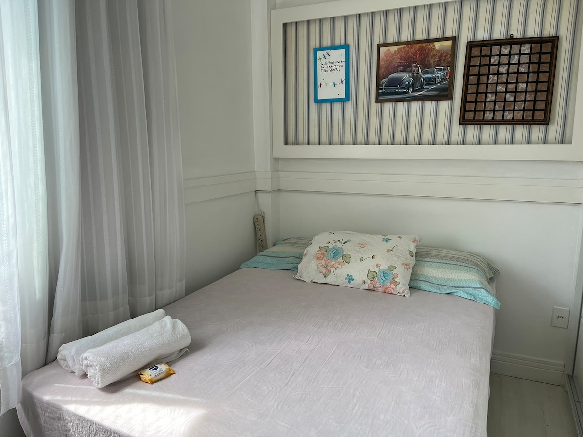 Pohodlná izba vybavená posteľou, ventilátorom a televízorom.