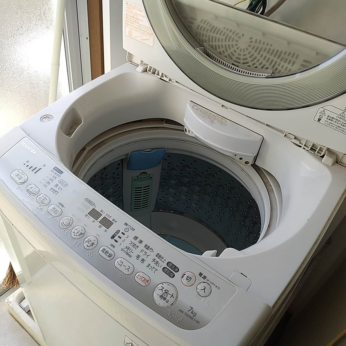 A modern washing machine is shown with an open lid, revealing the interior drum. The control panel features various settings and buttons, providing options for different wash cycles.
