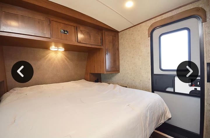 غرفة نوم رئيسية مقطورة (سرير كوين) مع باب إلى الخارج وباب بين غرفة المعيشة