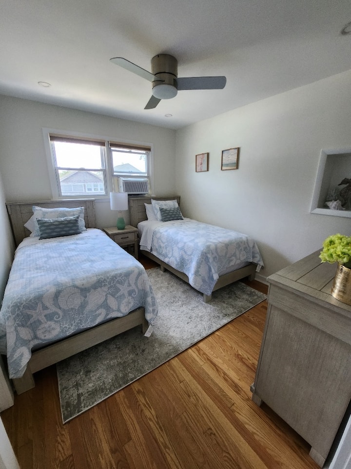 Bedroom 3 with 2 Single Beds, Ceiling Fan, Dresser, Smart TV & Closet for Storage. Closet contains Luggage Rack, extra pillows & extra linens and clothes hamper.