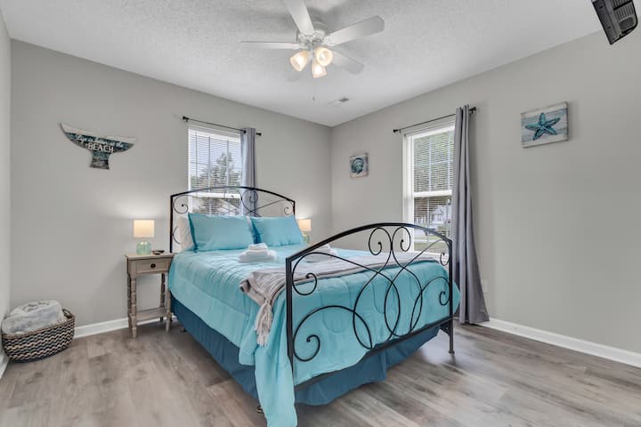 Kitanda cha ukubwa wa Malkia na Smart TV ukutani.