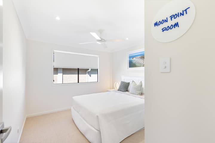 Спалнята в Moon Point разполага с красиво спално бельо с двоен размер и меки възглавници. Широк прозорец с блокирани щори носи сянка за спане. Спете под успокояващ крайбрежен арт печат и топло осветление. 