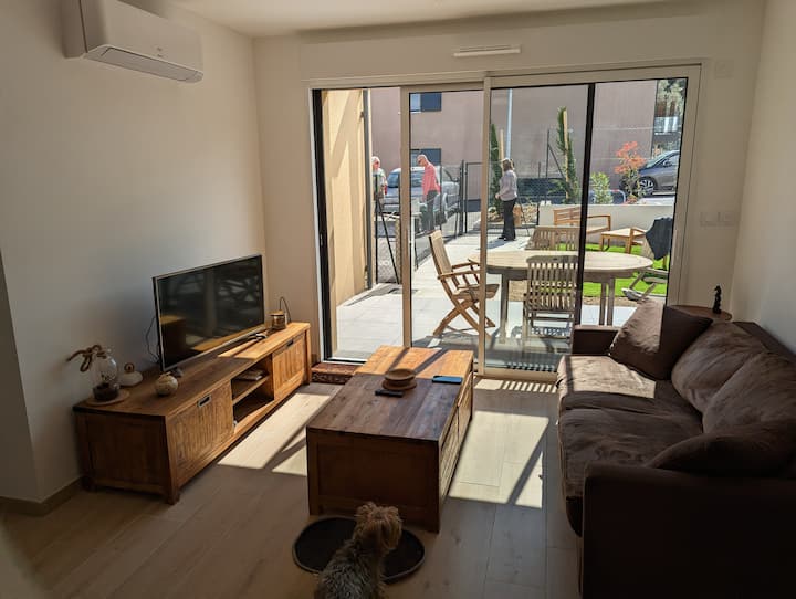 Ambient ndenjjeje me divan krevat, tavolinë kafeje, stendë televizori, televizor dhe kuti interneti.