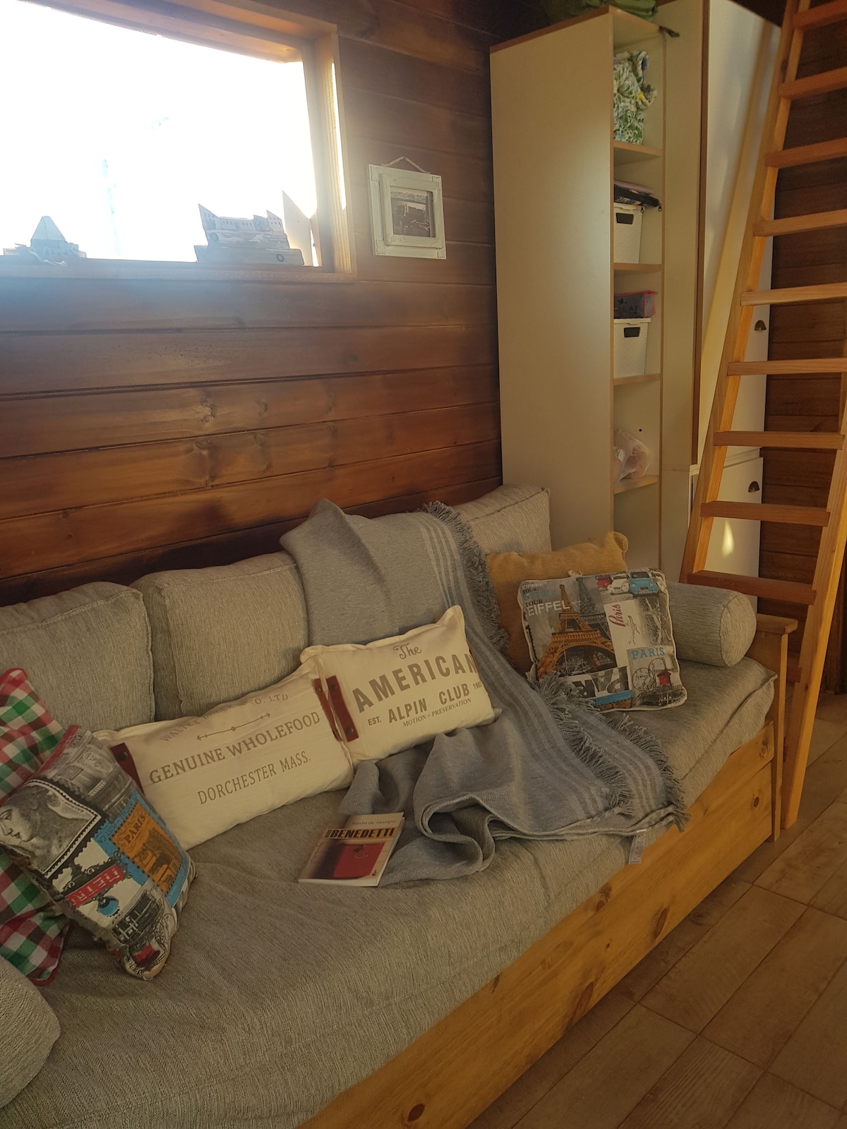 Kauč od 1 kvadratnog drva ukrašen jastucima na katu.
Ispod se nalazi još jedan krevet za jednu osobu.