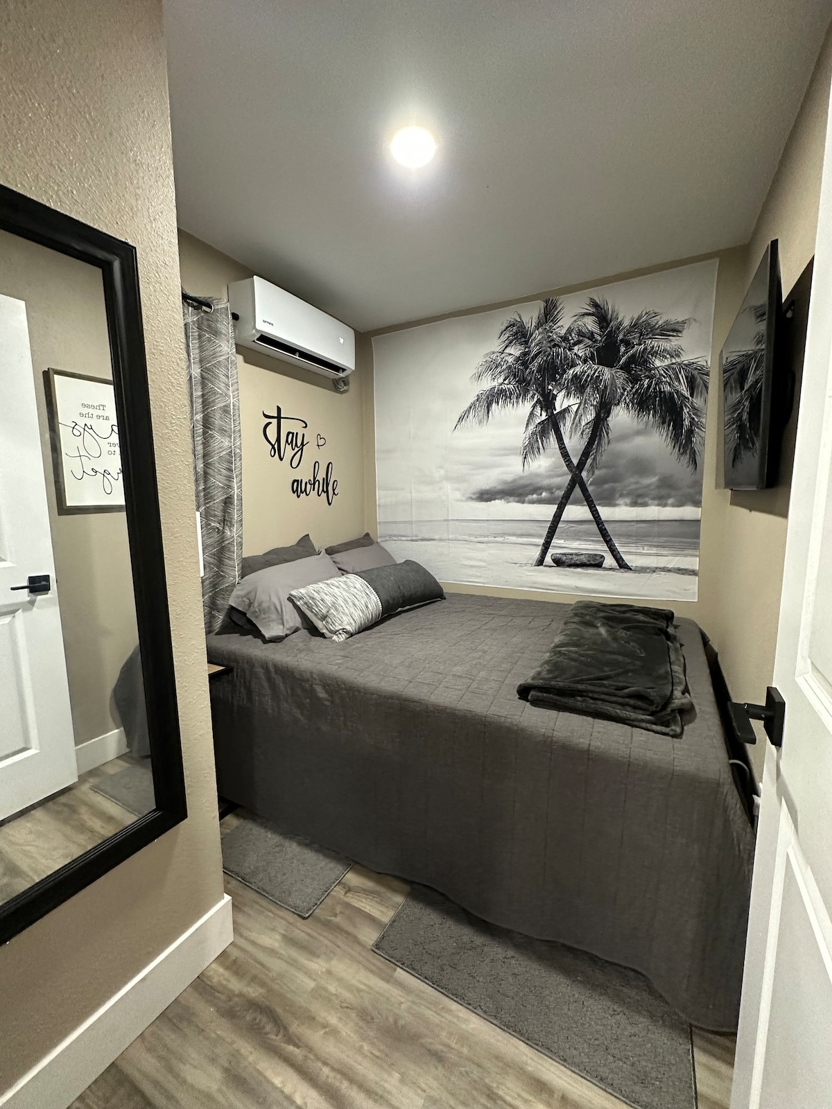 卧室配有一张标准双人床和一个带迷你分体式空调和电视的衣柜 