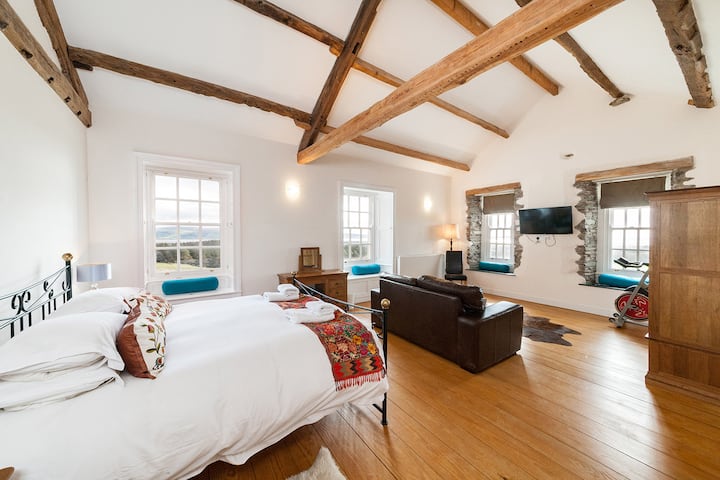 オリジナルの梁とダドンとアイルランド海の素晴らしい景色を楽しめる広々としたマスターベッドルーム。