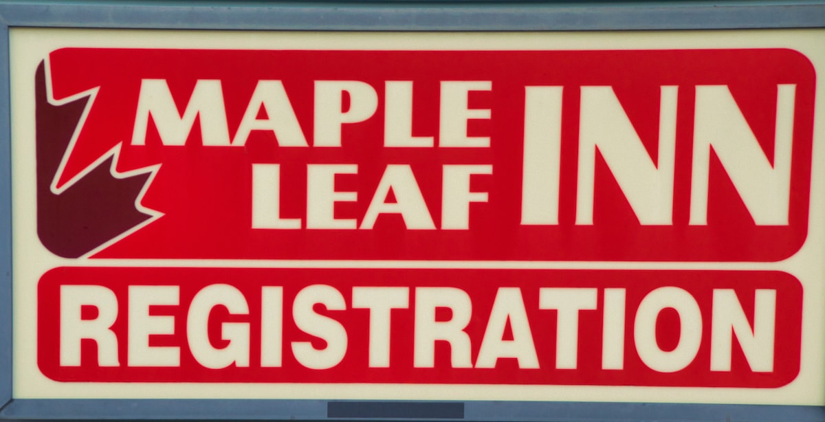A large sign for the Maple Leaf Inn is prominently displayed, featuring bold red letters indicating 'REGISTRATION.' The design includes a stylized maple leaf graphic, contributing to the overall branding of the inn.