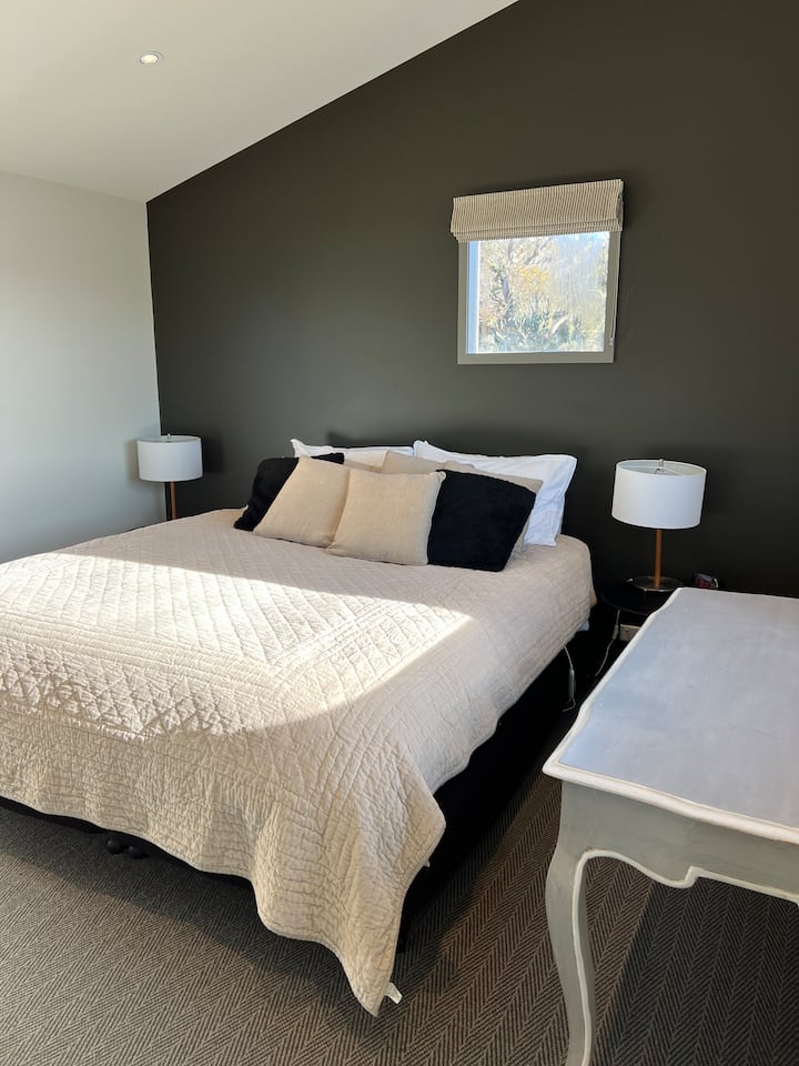 غرفة النوم الرئيسية (في الطابق الثالث) مع طاولات ومصابيح ومكتب بجانب السرير