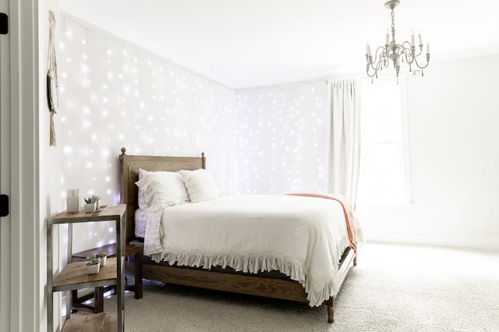 Cama queen en un dormitorio espacioso en la planta superior con un gran armario, una divertida silla colgante y un baño completo.