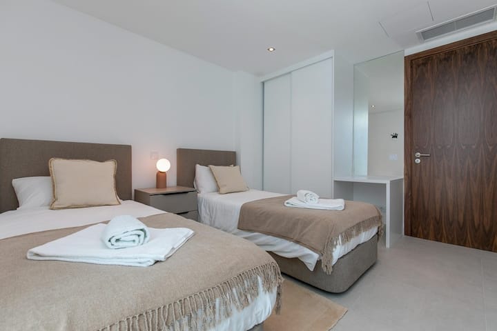 Dormitorio con dos camas individuales: uno de los dormitorios cuenta con dos camas individuales y acceso directo al patio exterior. Esta configuración proporciona una amplia luz natural y un cómodo acceso al aire libre.			