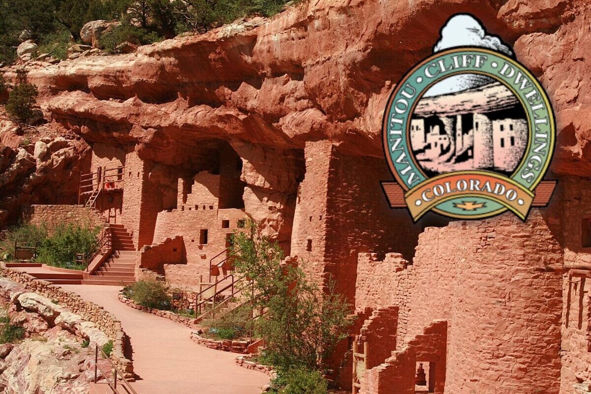 The image showcases the Manitou Cliff Dwellings nestled against a rocky cliff, featuring well-preserved adobe structures that reflect the unique architecture of ancient Native American dwellings. Lush greenery surrounds the pathways leading to the dwellings, inviting exploration of this historic site.