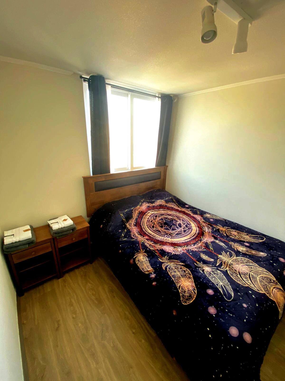 Habitación con cama de dos plazas, veladores, clóset y toallas de baño.