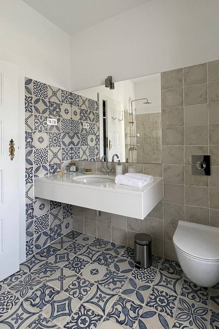Casa de banho com chuveiro, lavatório e azulejos portugueses: espaçosa e muito cuidada.